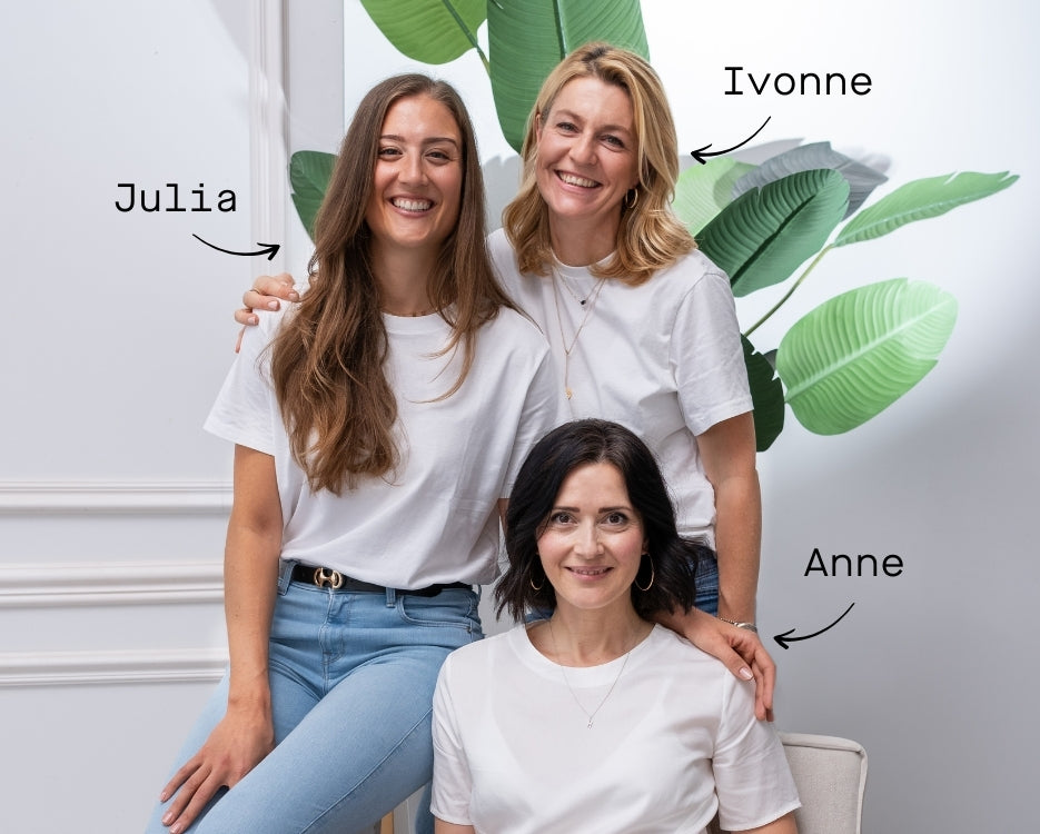 Drei Frauen, die Gründerinnen von FemBe, lachen in die Kamera, sie befinden sich in einem hellen Wohnzimmer Setting