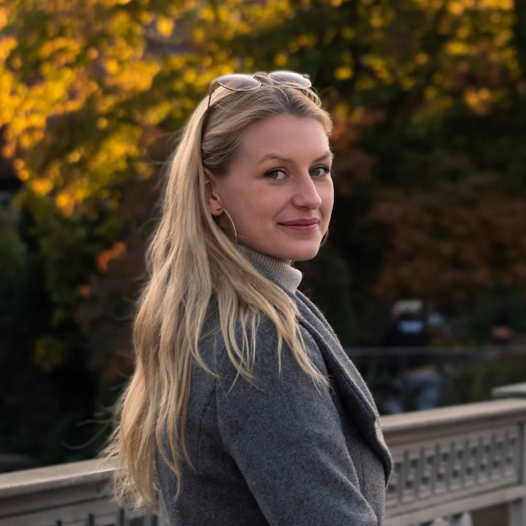 Eine blonde Frau im Portraitmodus lächelt in die Kamera