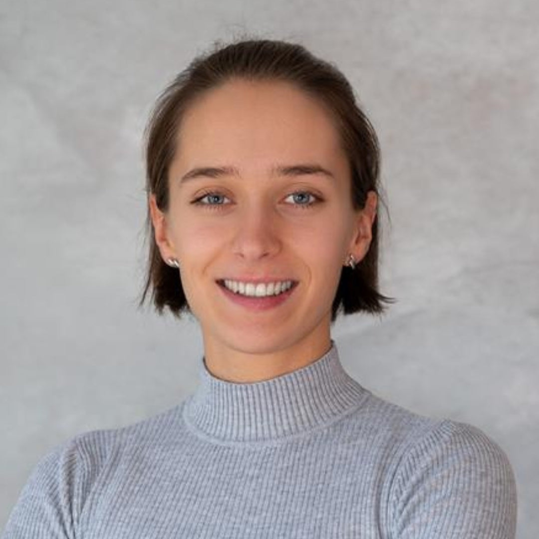 Eine dunkelhaarige Frau mit einem BobSchnitt im Portraitmodus lächelt in die Kamera